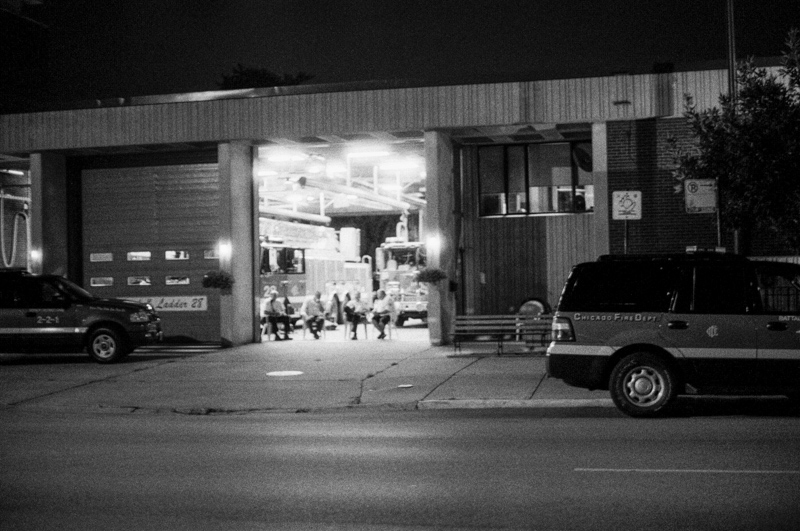 Firefighters sitting under an open garage door at night